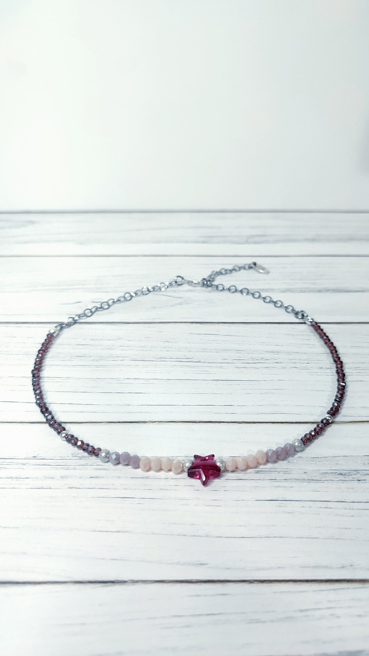 Vista completa delCollar realizado en distintos tipos de cristales en tonos malva y rosa, cuenta con una estrella de cristal en el centro.