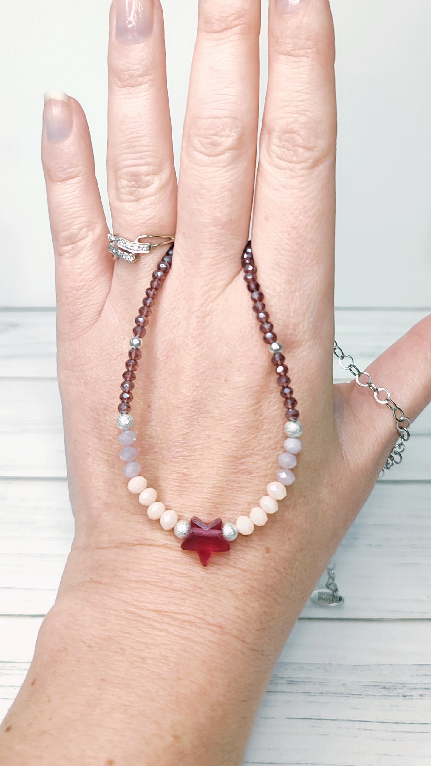 Detalle delCollar realizado en distintos tipos de cristales en tonos malva y rosa, cuenta con una estrella de cristal en el centro.