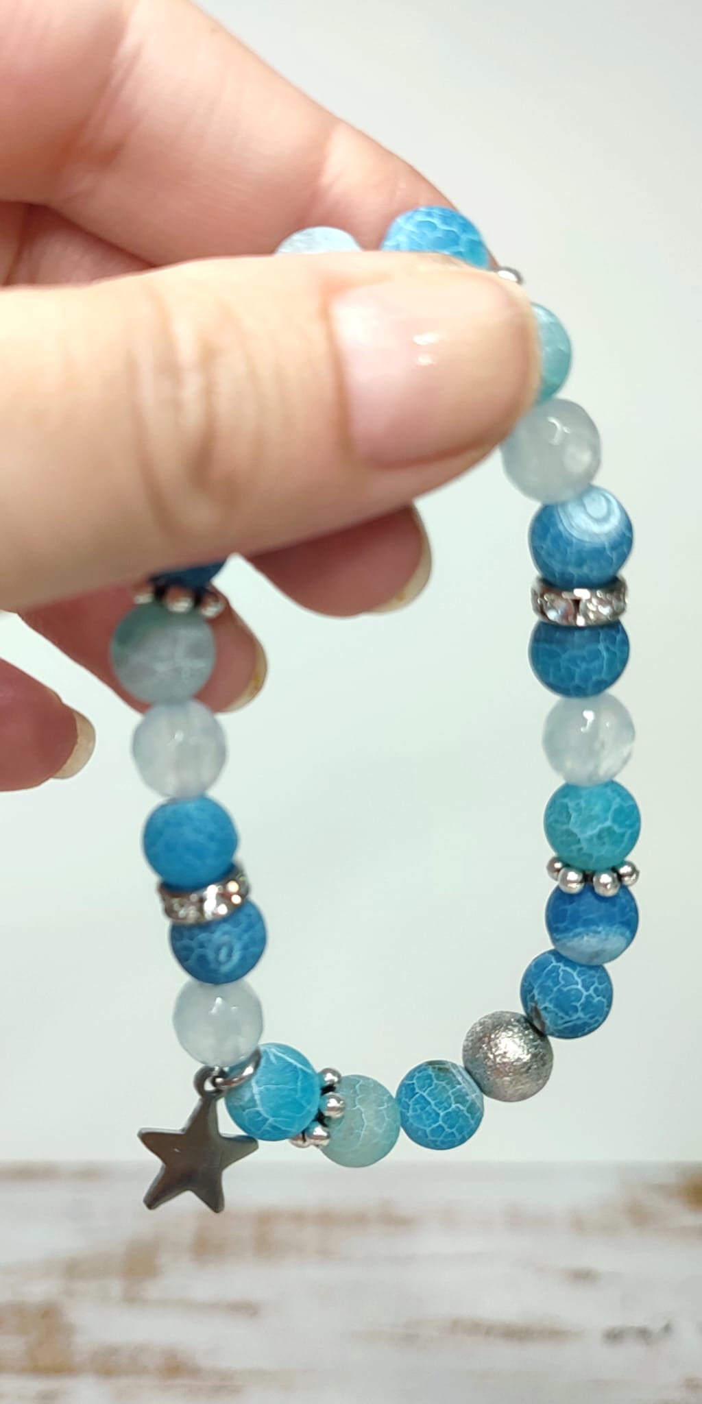 Disfruta con nuestra preciosa pulsera de calcedonia, ágata y jade, en un hermoso tono turquesa y azul claro. La perfecta combinación de piedras te llenará de serenidad y equilibrio. Ademas cuanta con una estrella de acero con la palabra "Luck". Lleva contigo esta pulsera y déjate envolver por su exquisita energía.