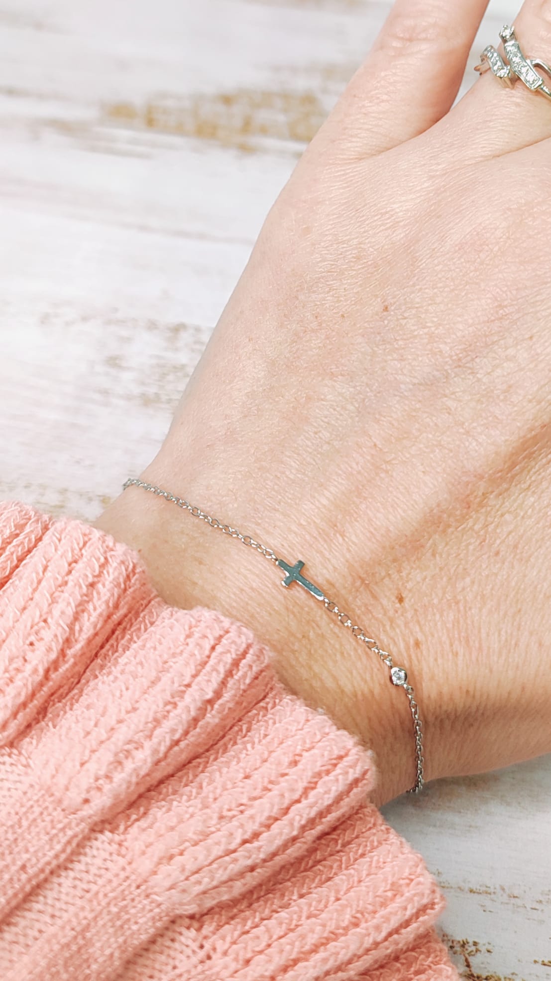 Vista en la muñeca de la pulsera, se ve el detalle de la cruz y el pequeño cristal