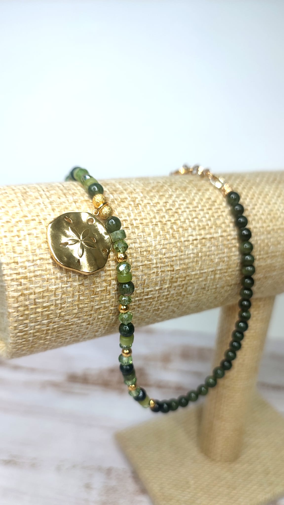 Detalle de cerca de Collar de Minerales en tonos verde con medalla rustica dorada con flor en el centro