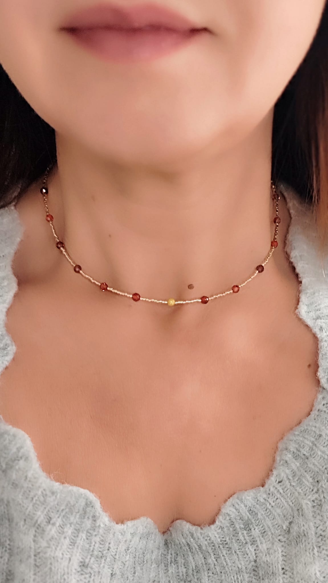 Collar en tonos dorado y rojo cobrizo visto en escote de mujer